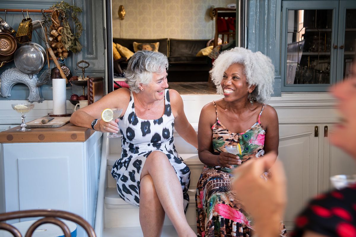 dve ženski, ki skupaj sedita in se smejita na koktajlu