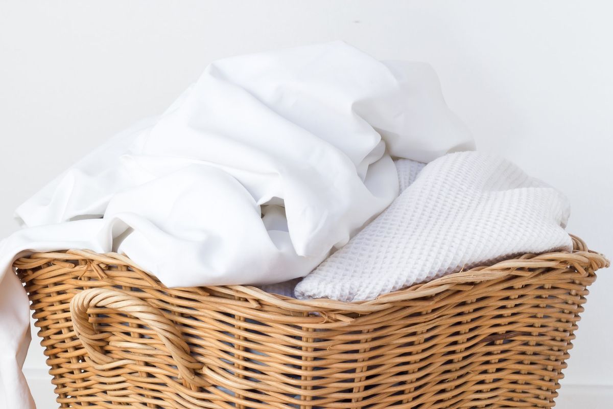 saubere weiße Bettwäsche und Handtücher im Korb