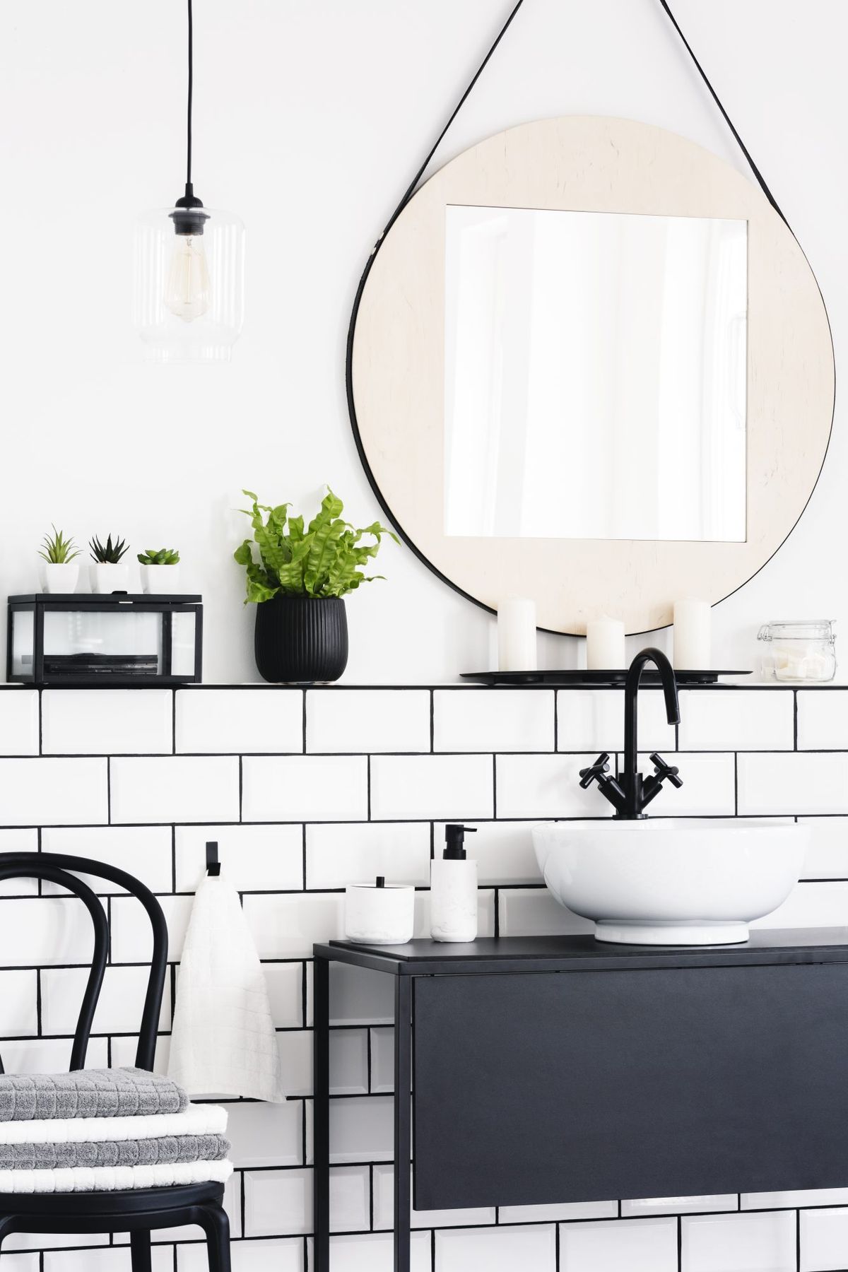 toaletni interijer sa ogledalom, biljkom, stolicom i crnim ormarićem
