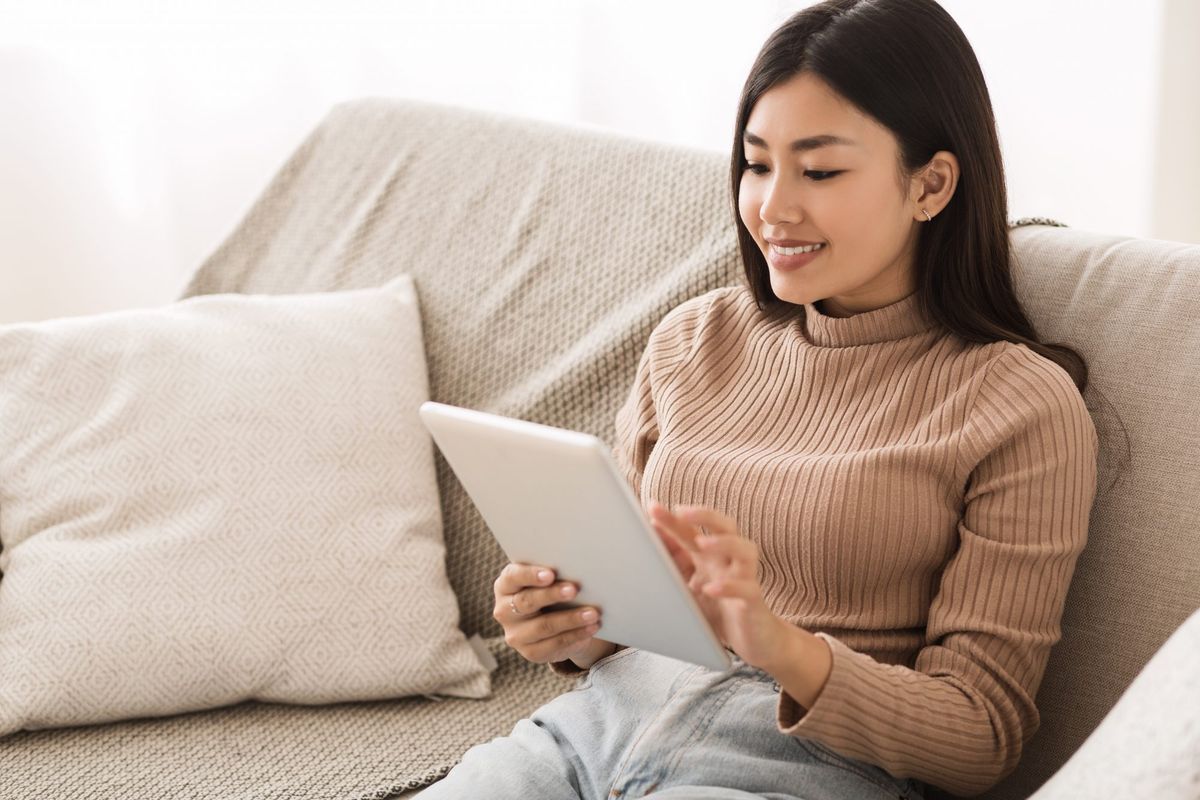 mlada ženska, ki na tabličnem računalniku bere e-knjigo