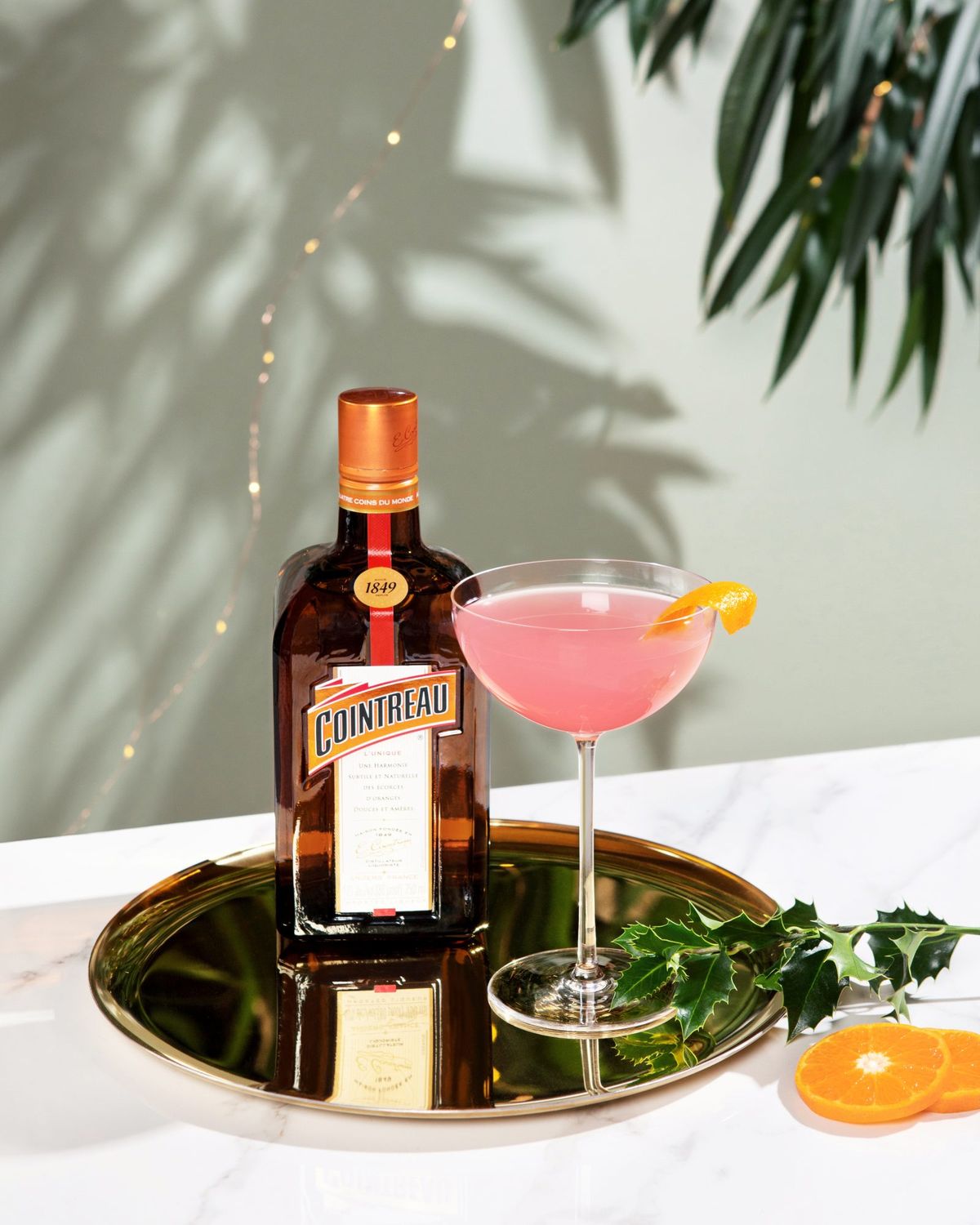 pullo Cointreaua ja lasi vaaleanpunaisella cocktaililla messinkilevyllä