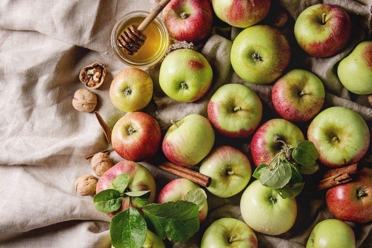 izbor jabolk na platneni krpi z loncem medu, orehov in cimetovih palic