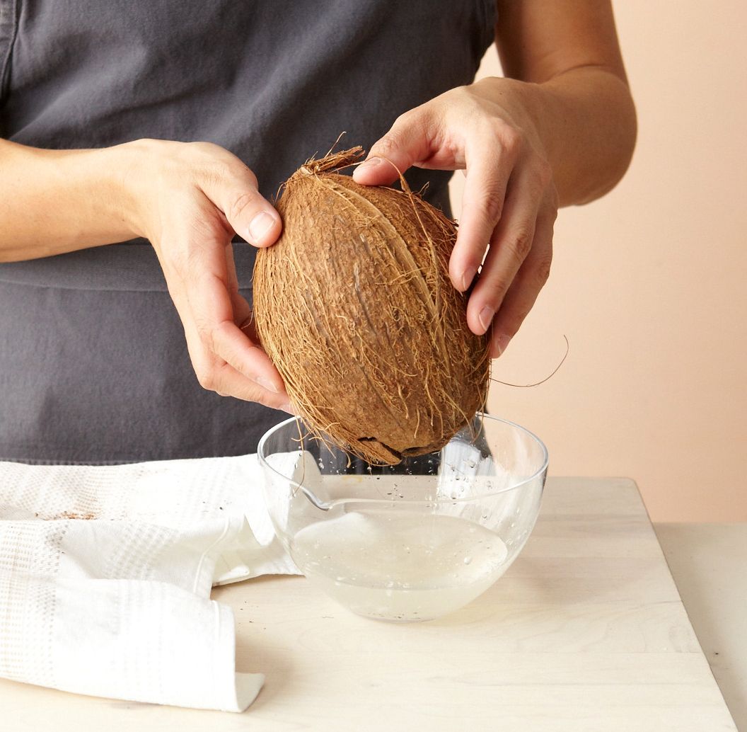 käed hoiavad kookospähkli kaussi vett