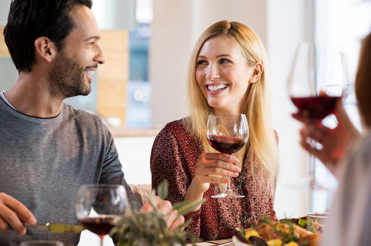 Lachende Freunde beim Abendessen mit Wein