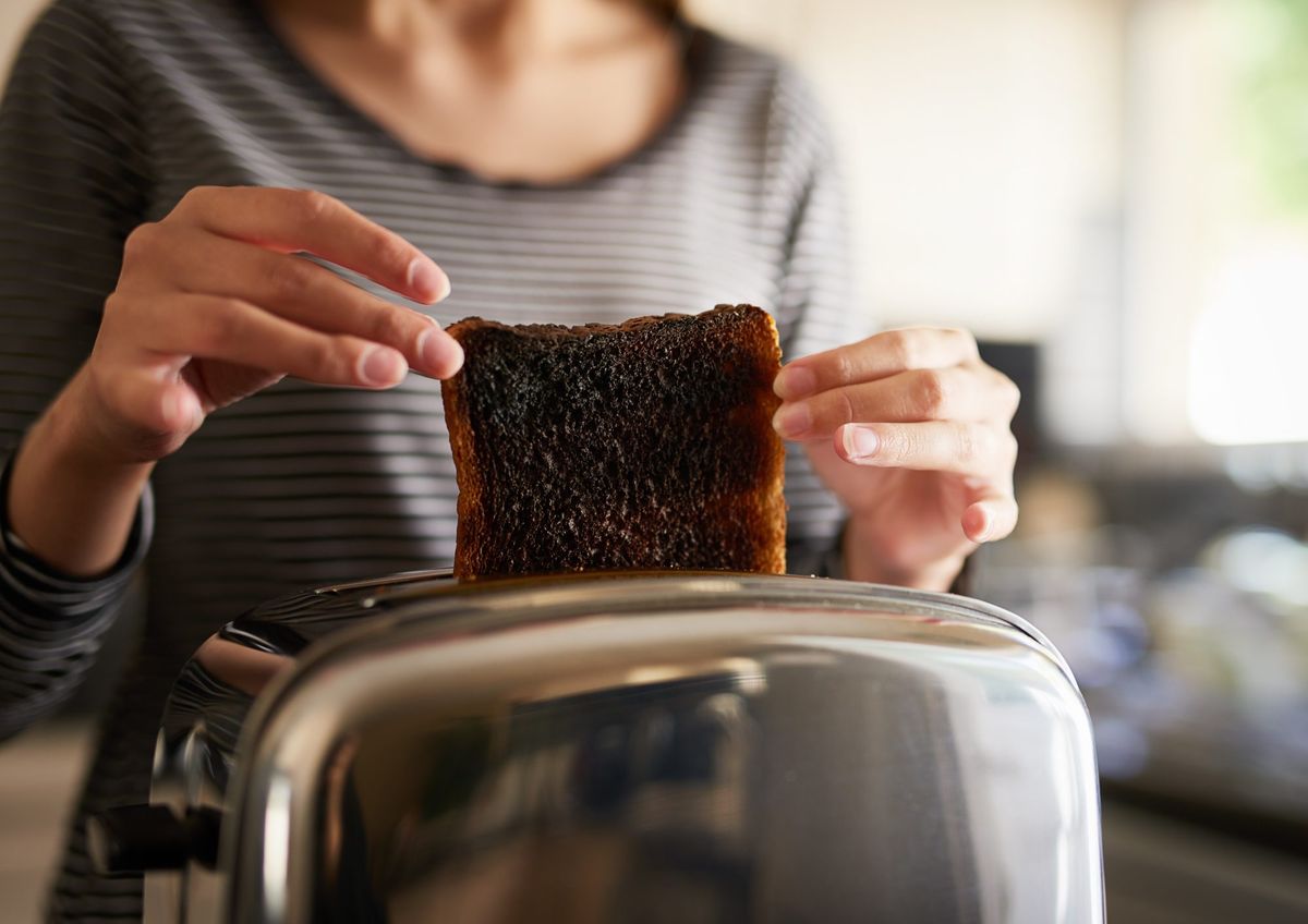 Frau entfernt verbrannten Toast aus einem Toaster