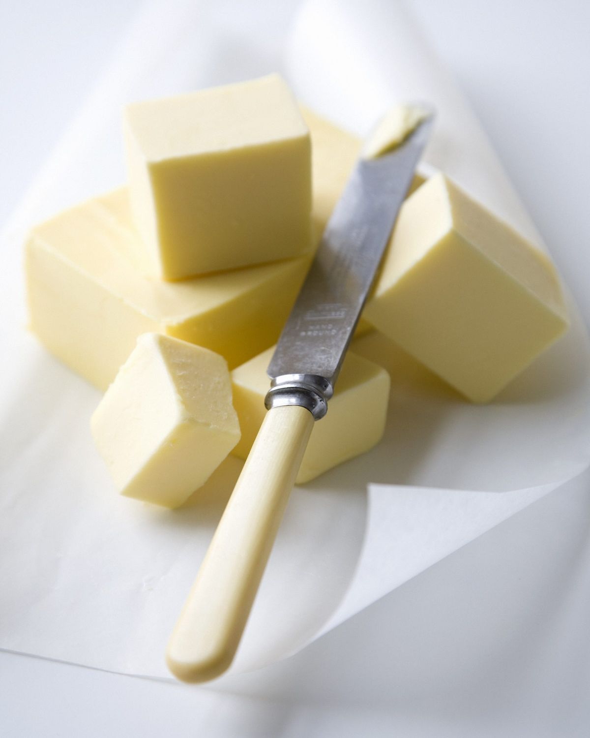 Blocs de mantega i ganivet de mantega sobre paper vegetal