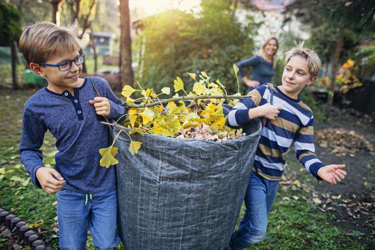 zwei Jungen tragen eine wiederverwendbare Tasche voller Blätter