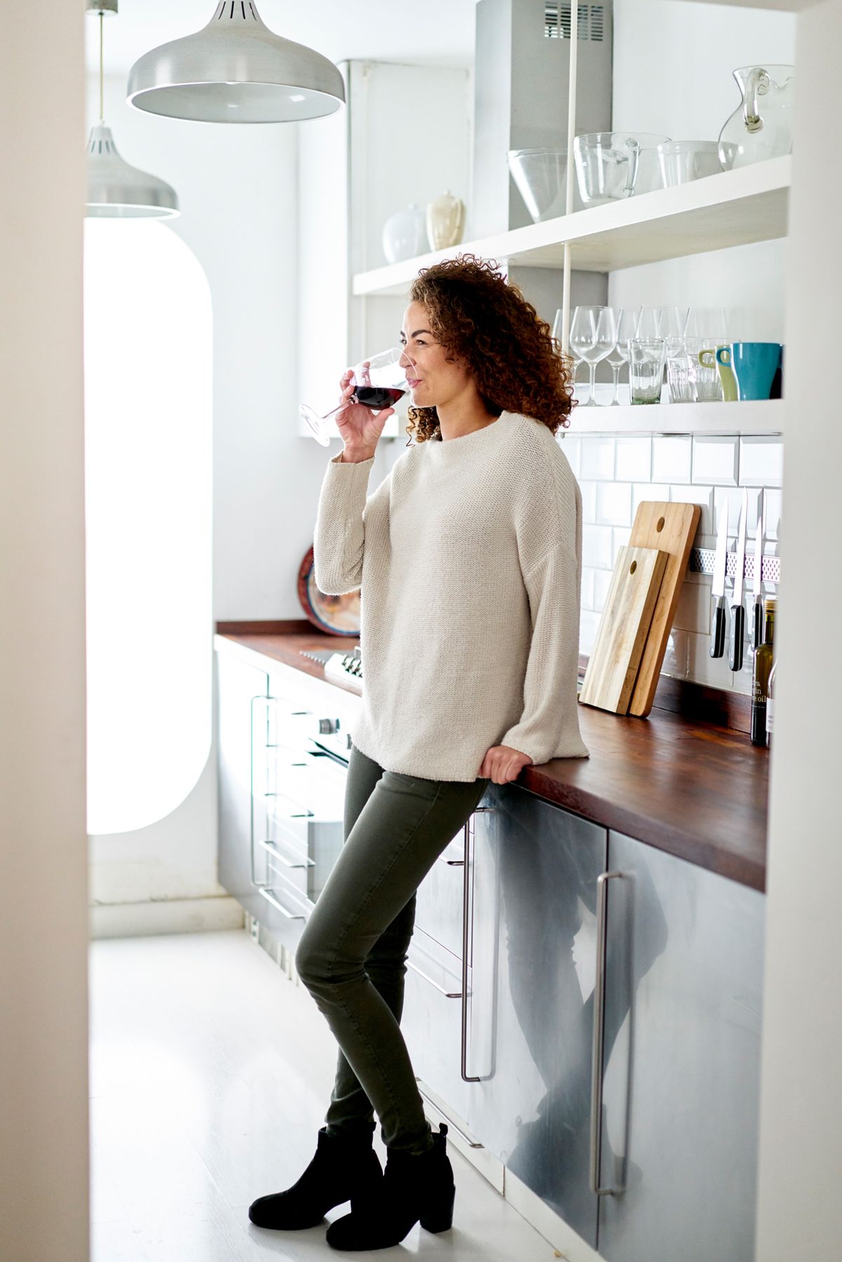 naine seisab köögis ja joob leti peale punast veini