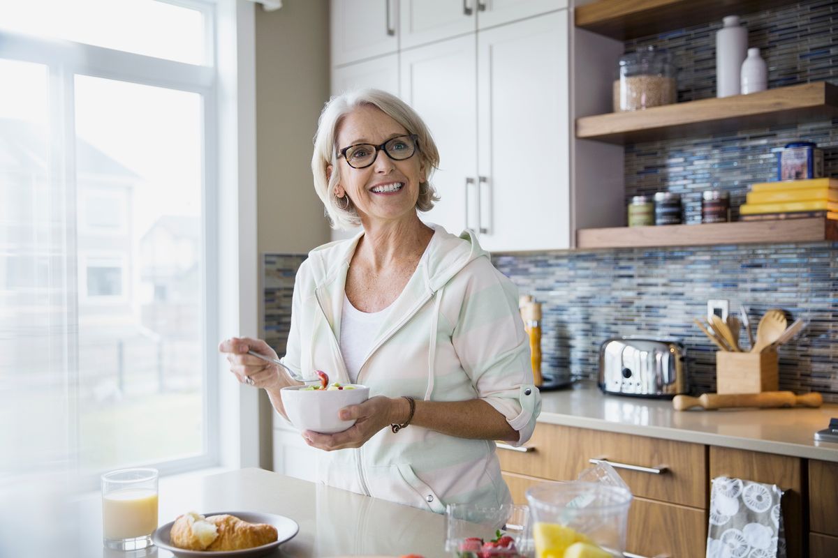 Dona menjant amanida mentre està parat a la cuina